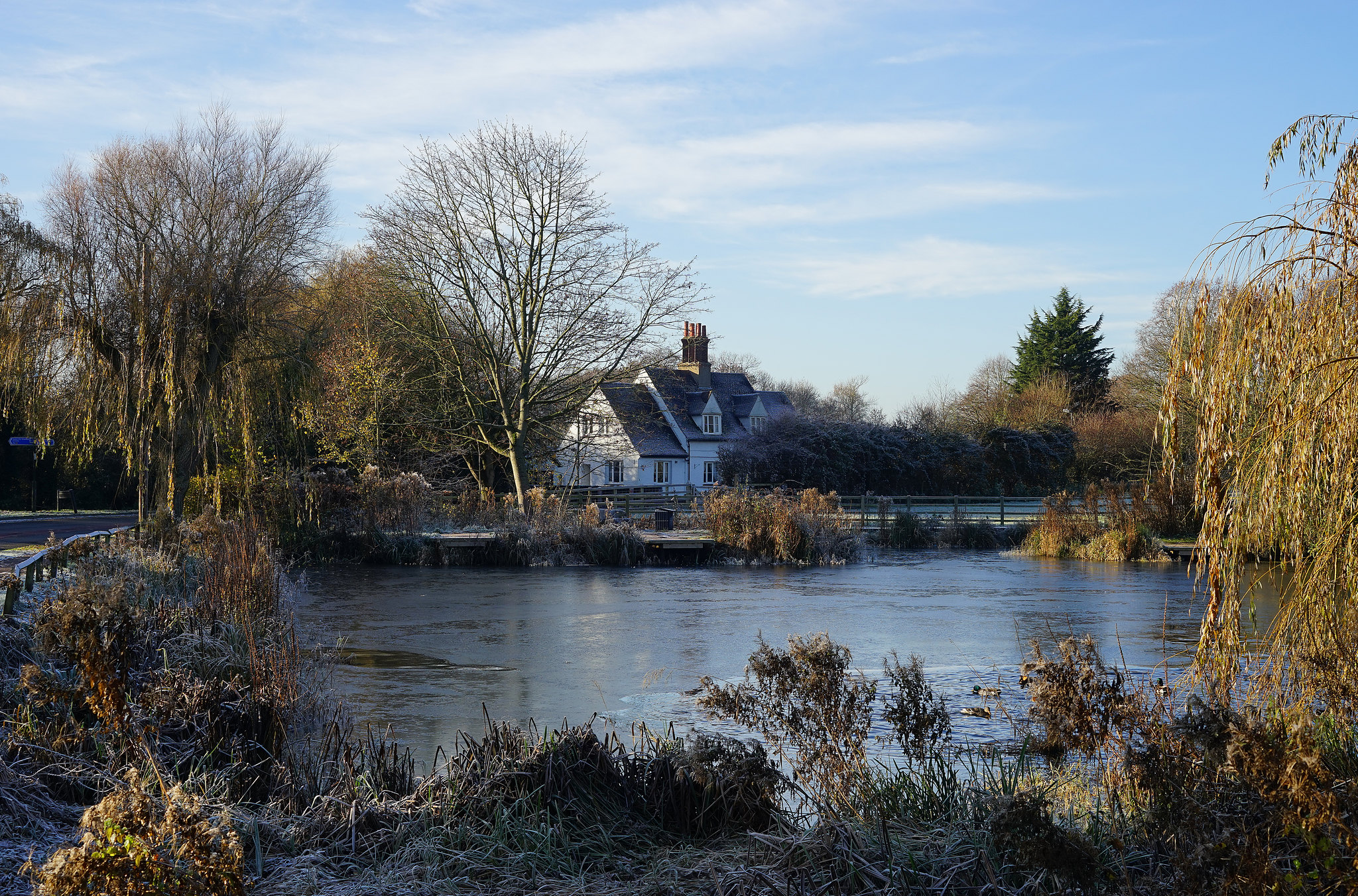 Lake in Letchworth on a bright day with a white property in the background.